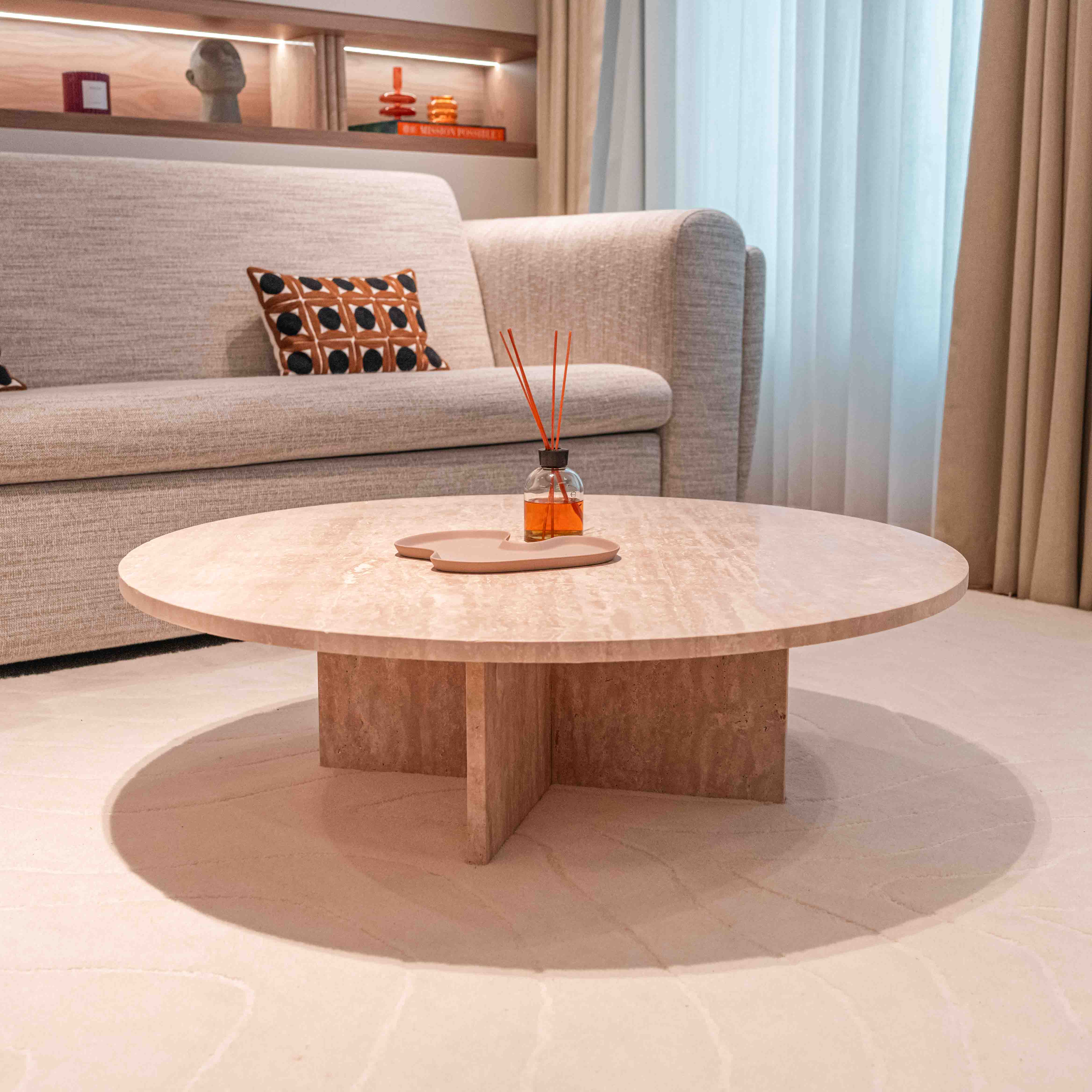 table basse en travertin beige avec plateau rond et pied croix